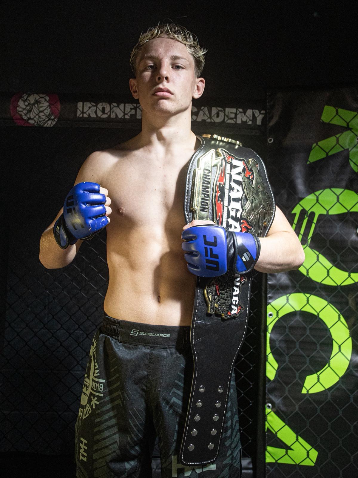 Elite MMA coach holding NAGA champion belt at Iron Fist Academy